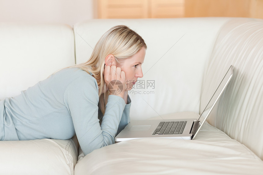沙发上躺着笔记本电脑的女人的侧视角图片