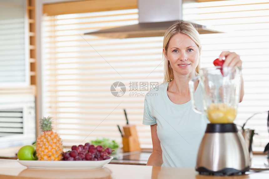 女人把草莓扔进搅拌机图片