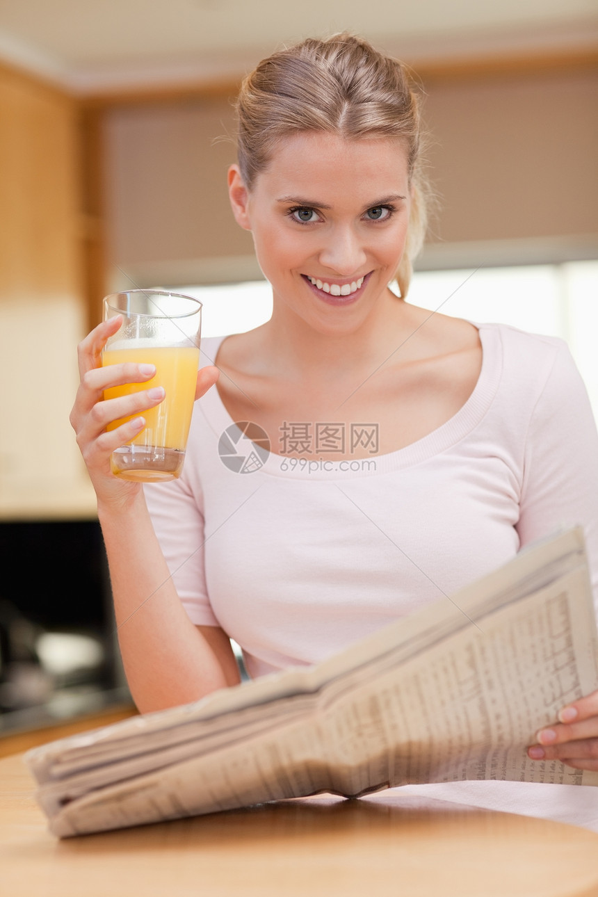 一个女人在喝果汁时看新闻的肖像图片