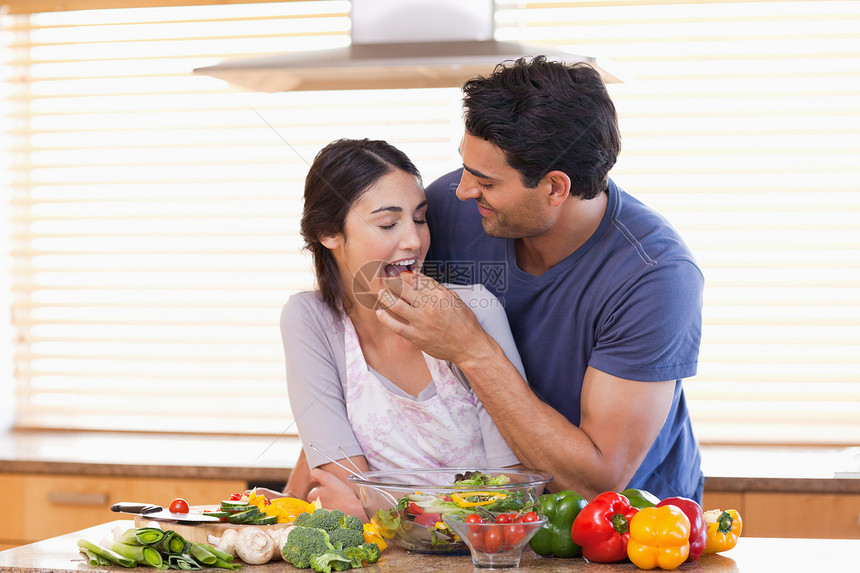 男人喂养他的妻子素菜素食者厨房围裙丈夫胡椒夫妻烹饪准备乐趣图片