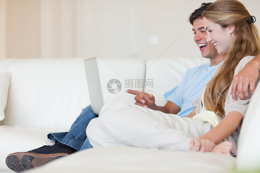 使用笔记本电脑的幸福情侣夫妻丈夫网络年轻人互联网长椅闲暇微笑女性沙发图片