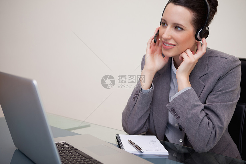 女商务人士 头戴耳机坐在她的办公桌前图片