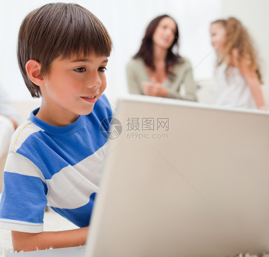 男孩在背后与家人玩电脑游戏;他的家人在他身后图片