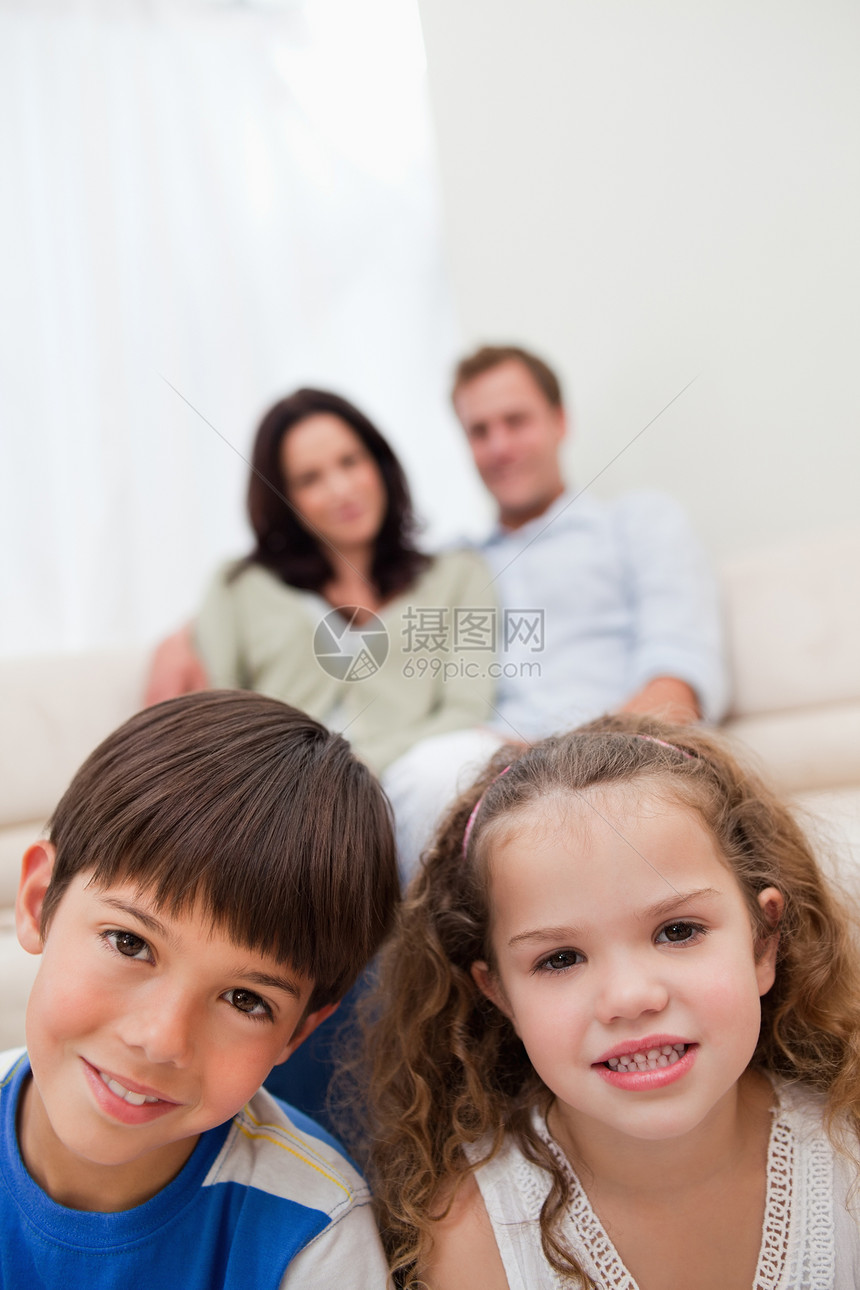 儿童坐在起居室里 父母在他们身后图片