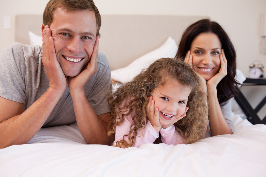 一起躺在床上的微笑的家庭男性拥抱女孩们女性外表团结快乐幸福枕头就寝图片