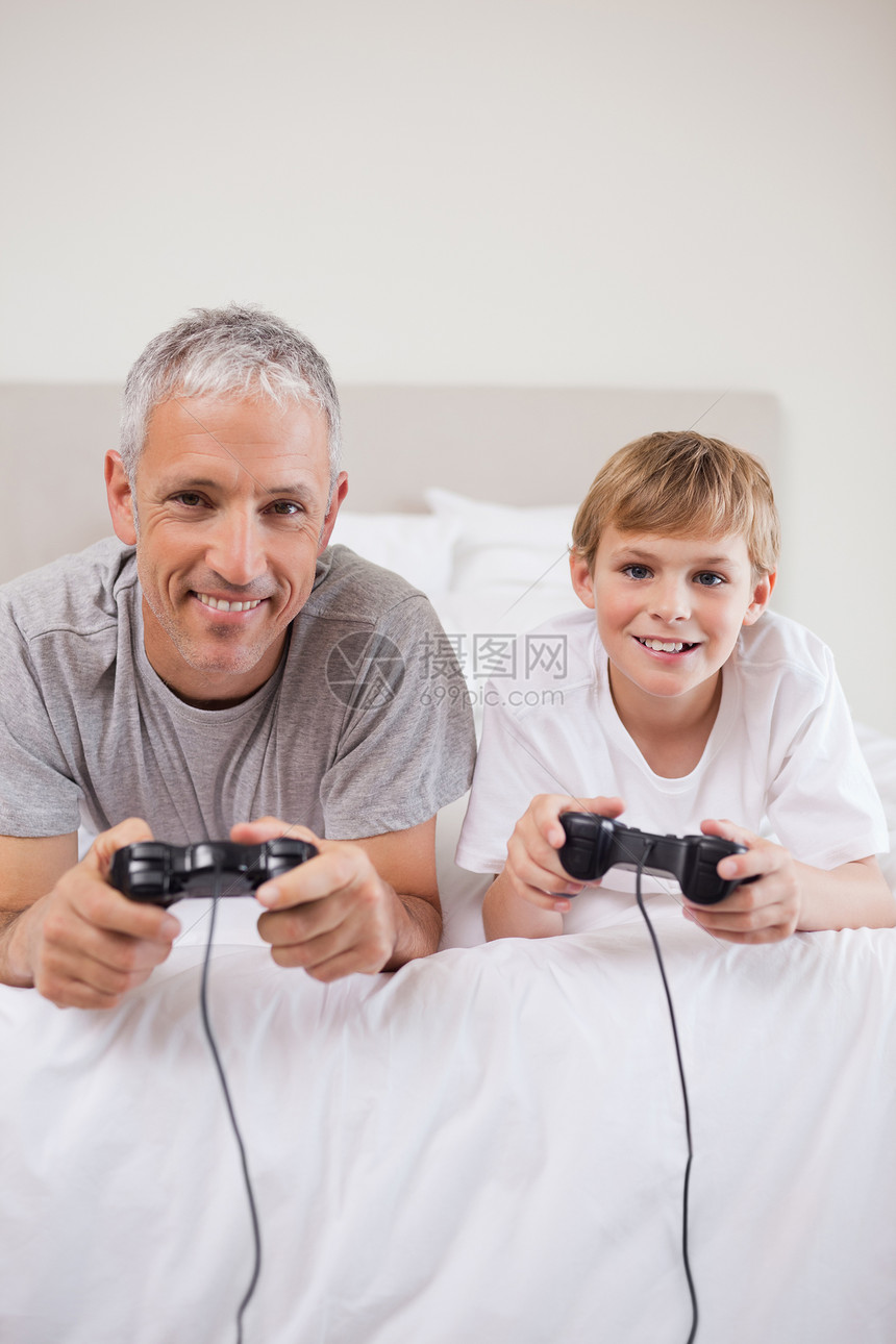 一个男孩和他父亲玩电子游戏的肖像游戏闲暇乐趣控制器竞争安慰男孩们快乐喜悦电子产品图片
