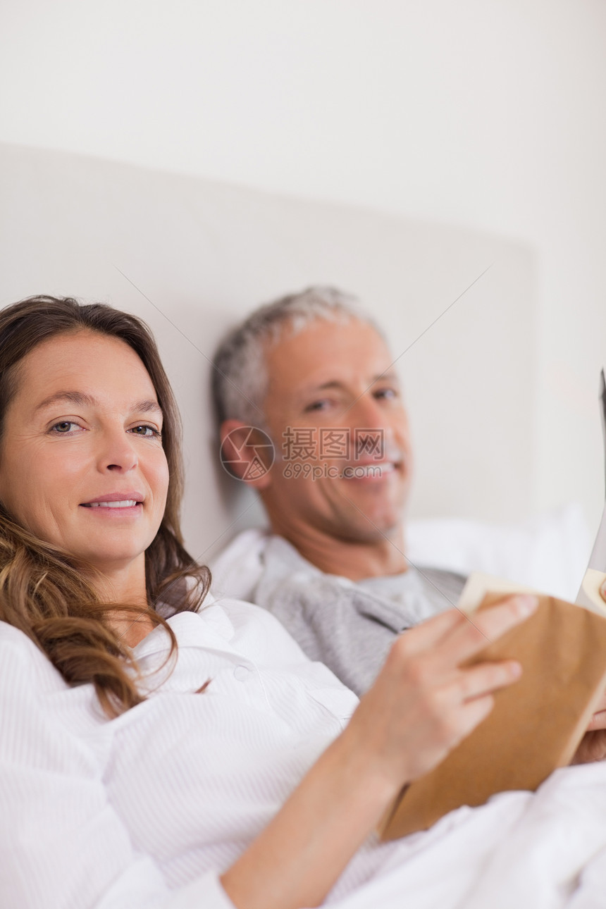 丈夫在读一本书时 妇女看书的肖像妻子夫妻卧室享受乐趣团结男人说谎男朋友闲暇图片
