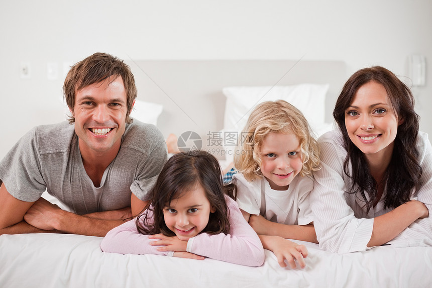 躺在床上的微笑的家庭兄弟姐妹家长拥抱乐趣儿子喜悦女性姿势丈夫男孩们图片