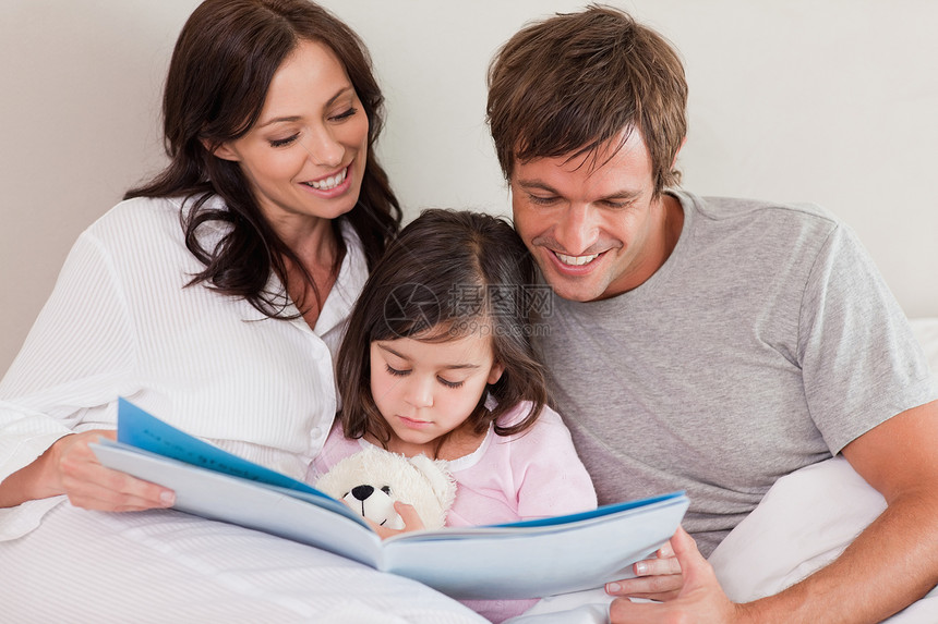 快乐的父母读一个故事给女儿听图片