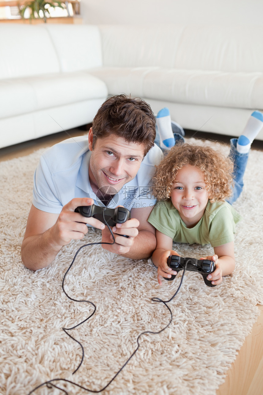 一个男孩和他父亲玩电子游戏的肖像乐趣快乐中年人两个人童年男人软垫地面家庭视频图片