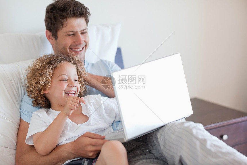 在床上使用笔记本电脑的父亲和子女图片