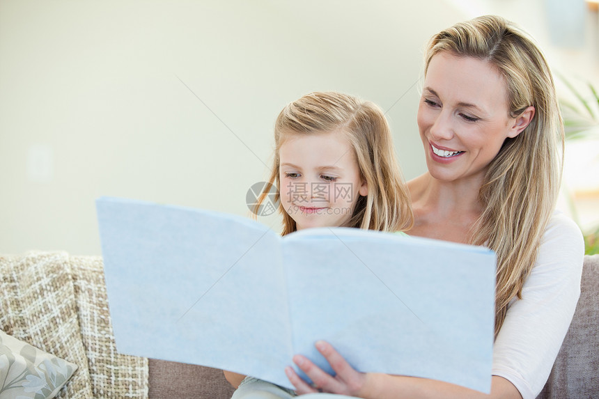 母亲和女儿在沙发上阅读团结客厅快乐感情故事享受长椅乐趣亲热孩子图片
