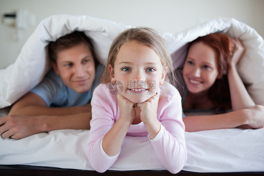 和父母一起躺在床上的快乐女孩图片