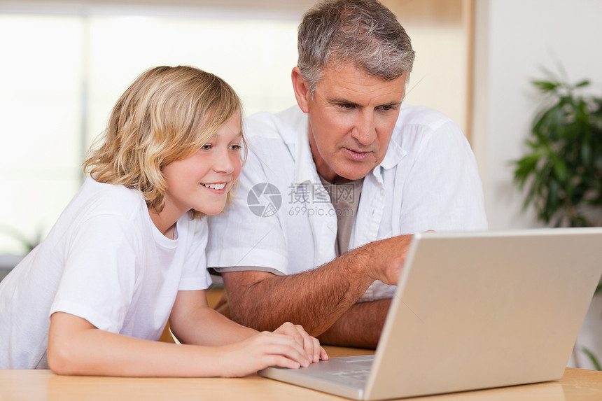 父亲和儿子在厨房用笔记本电脑图片