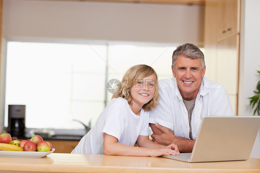 父亲和儿子用笔记本电脑微笑图片