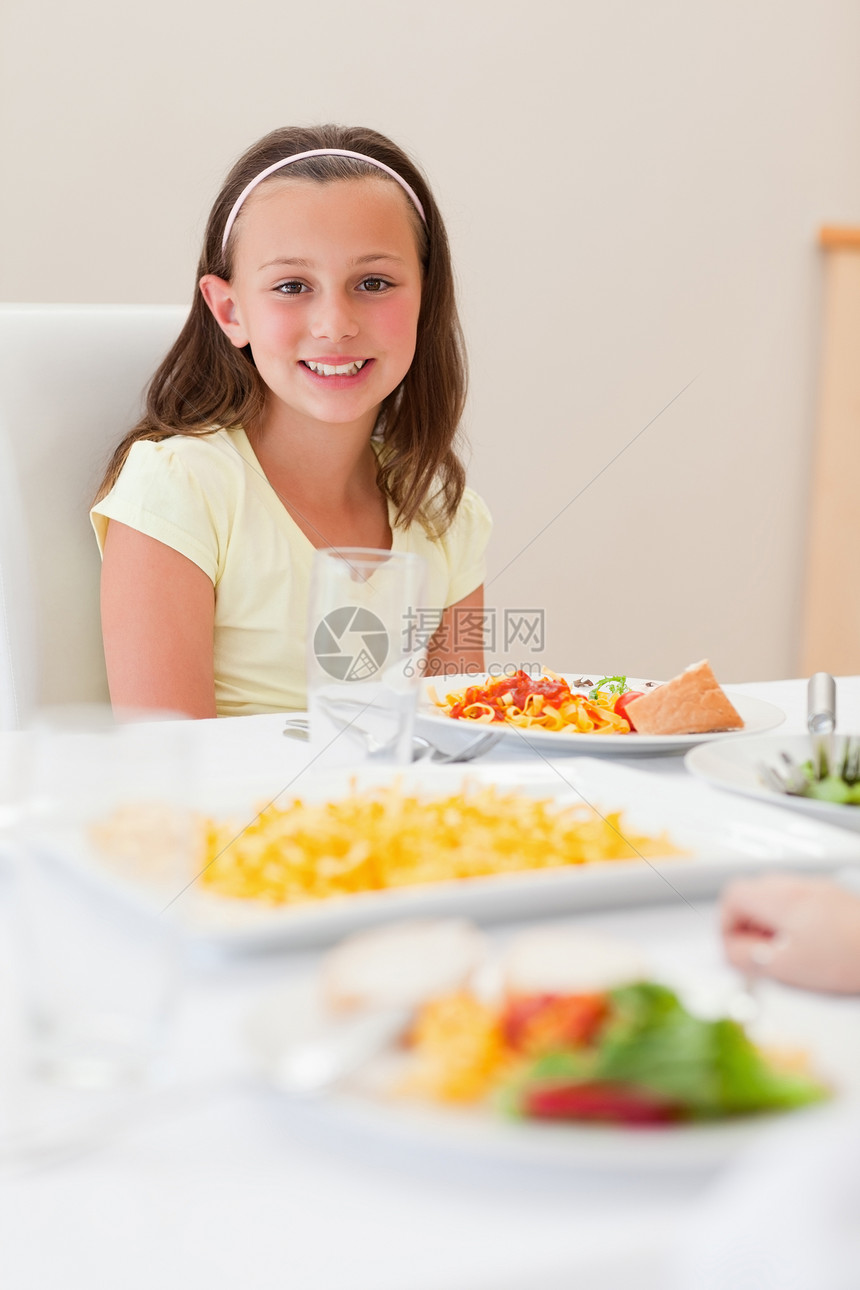 坐在晚餐桌边的微笑的女孩图片