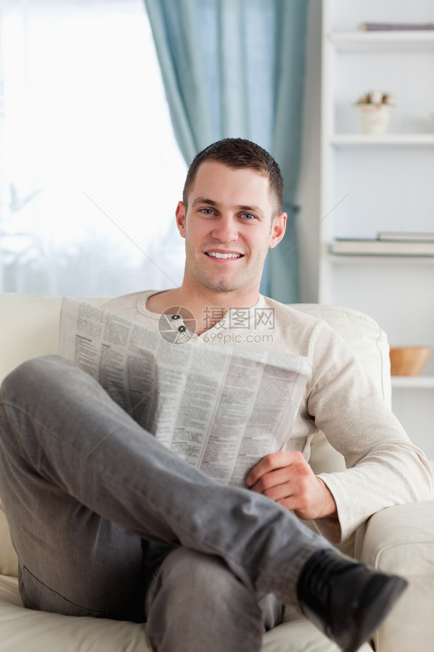一个微笑的人在看报纸的肖像白色水平房间享受长椅休息室外表沙发阅读闲暇图片