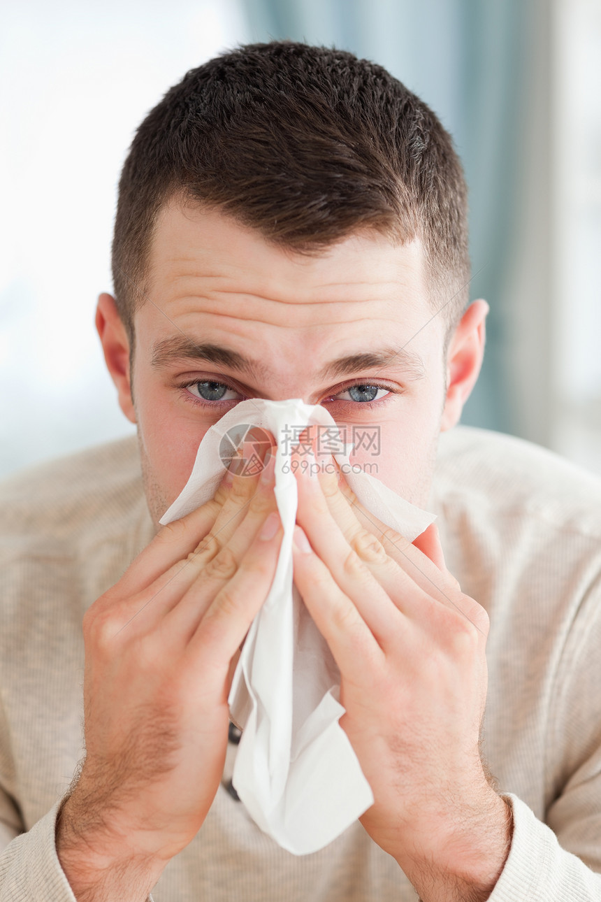 一个男人吹鼻涕的肖像感染手帕花粉保健症状沙发长椅年轻人组织卫生图片