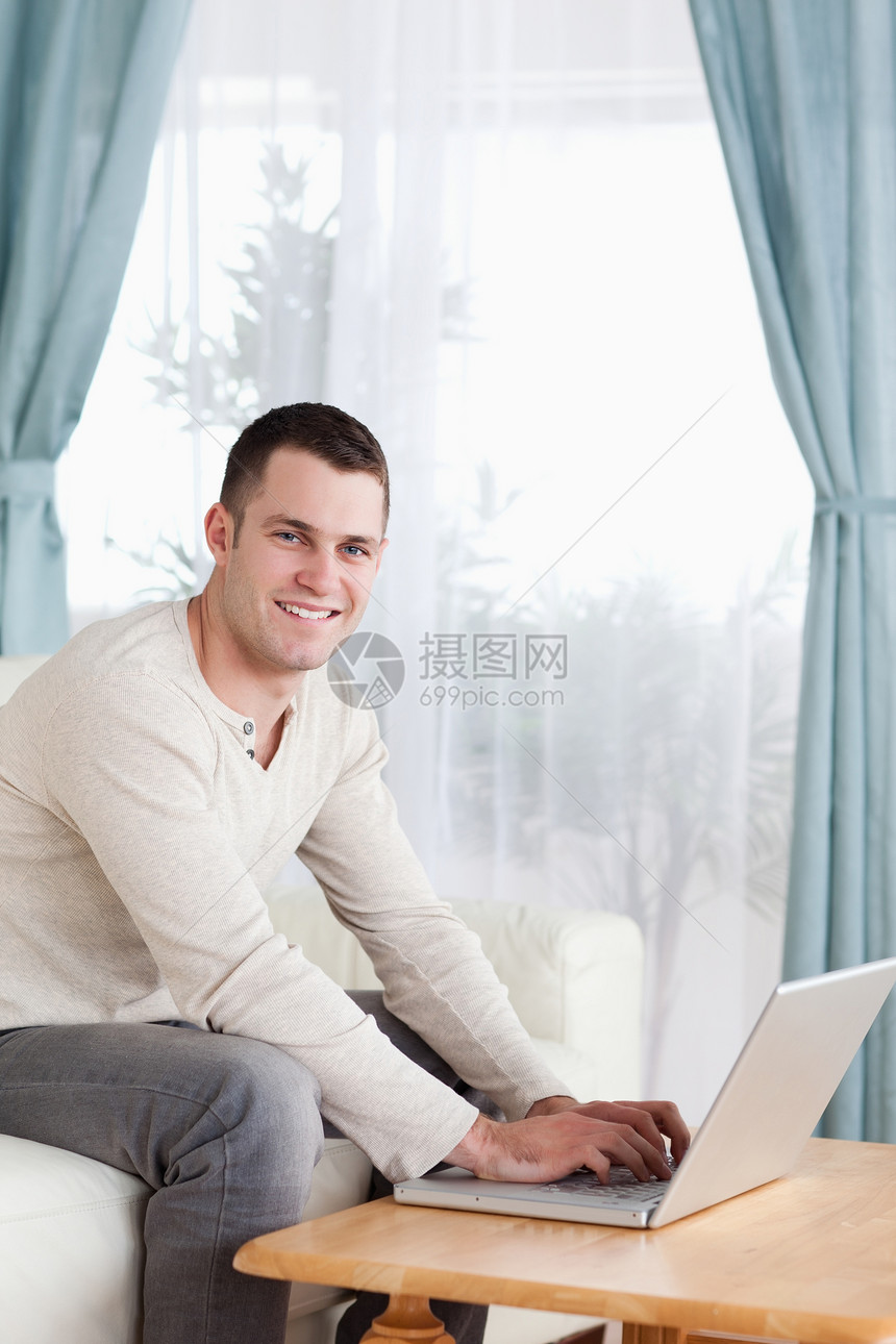 一个微笑的男人在笔记本电脑上打字的肖像图片