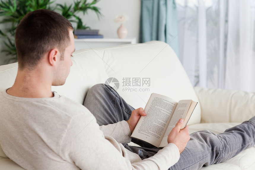 一个躺在沙发上看书的男人的肖像图片