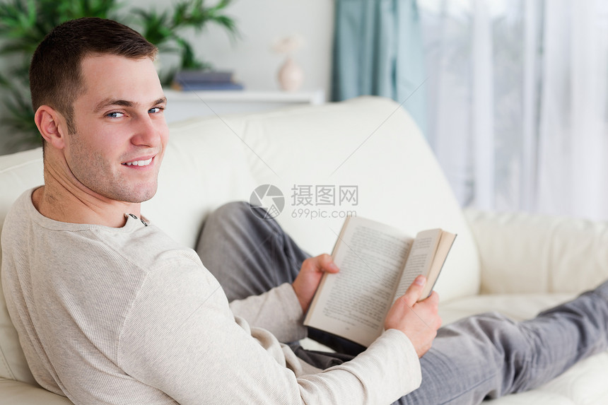 一个躺在沙发上 拿着一本书的男人的肖像图片