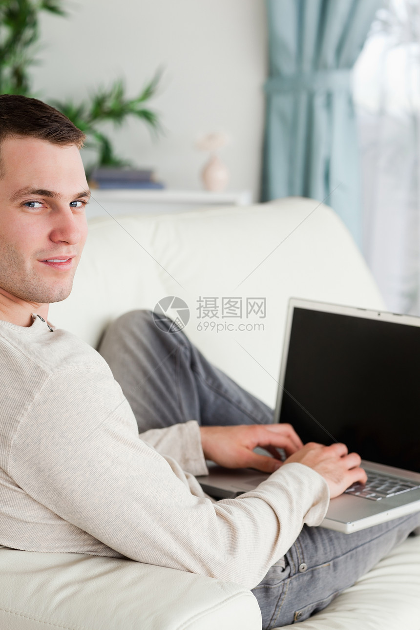 一个用笔记本电脑躺在沙发上的男人的肖像图片