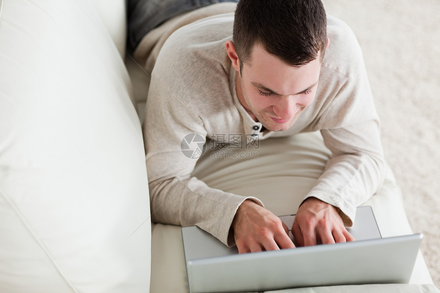 年轻人躺在沙发上用笔记本电脑图片
