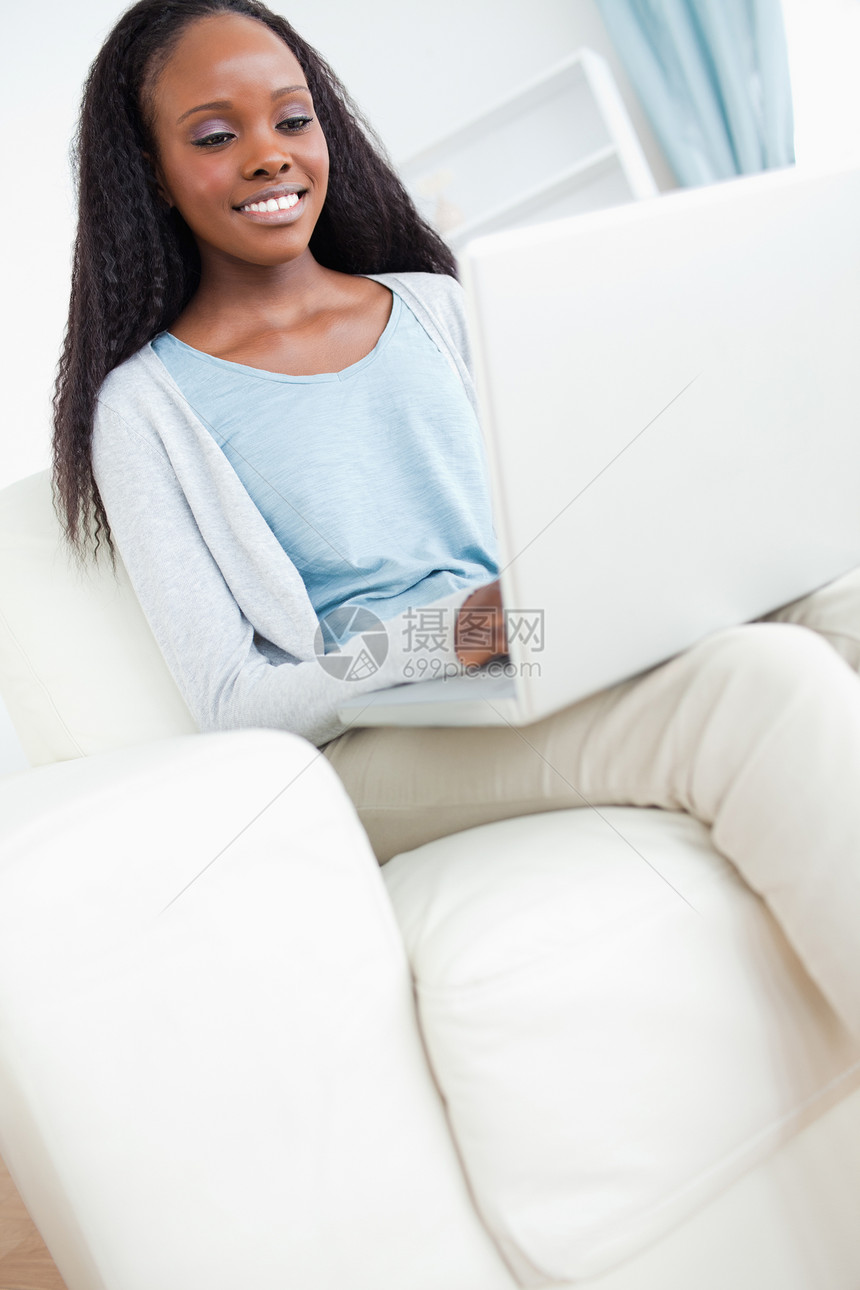 青年妇女用笔记本电脑坐在沙发上图片