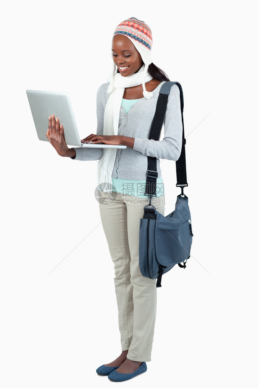 带笔记本电脑和冬衣女学生的侧边视景图片