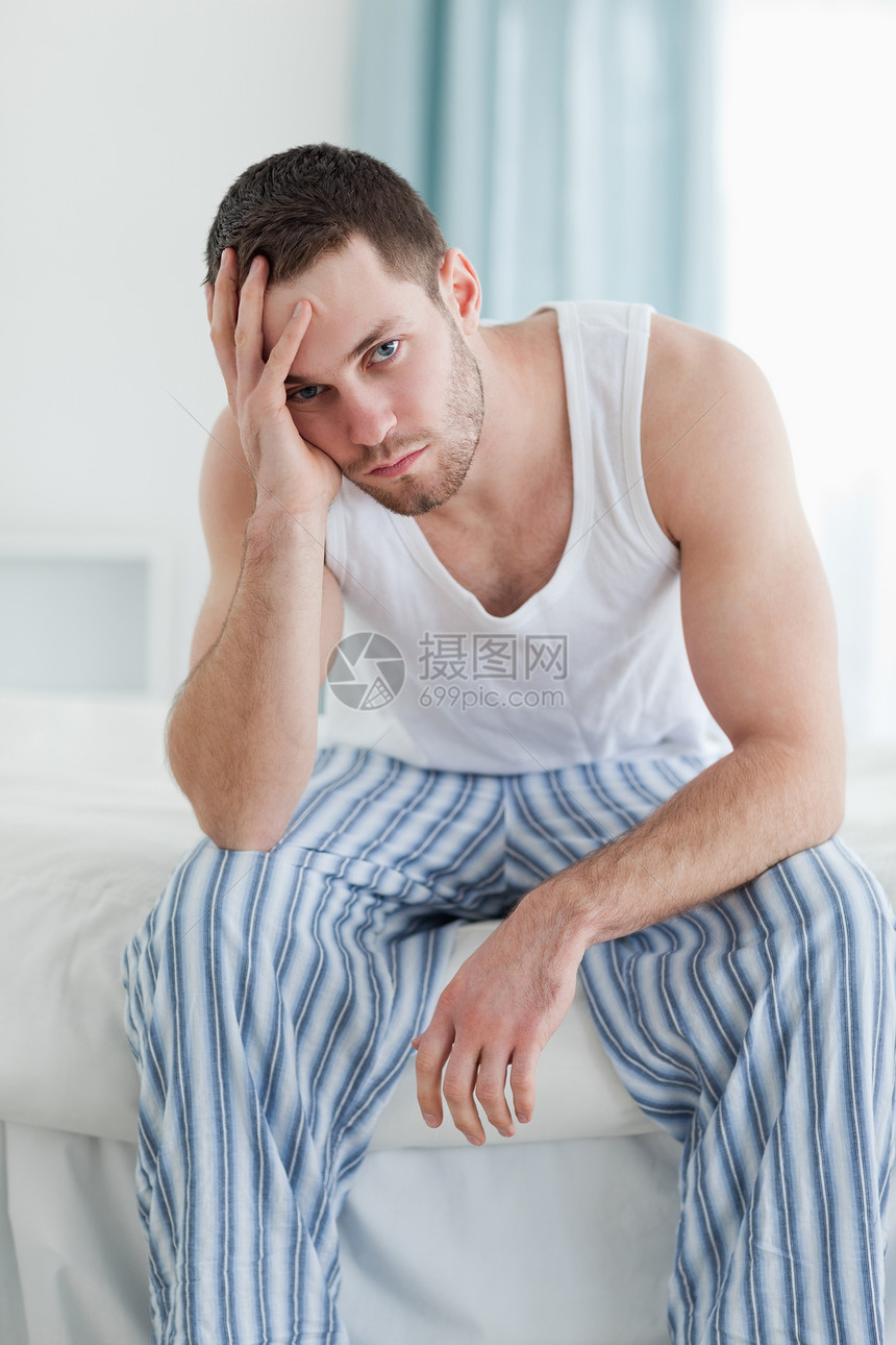 一个压抑的男人坐在床上的肖像图片
