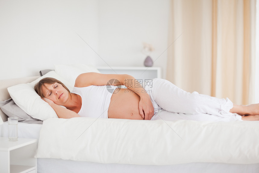 美丽的孕妇躺在床上休息时 在放松着图片