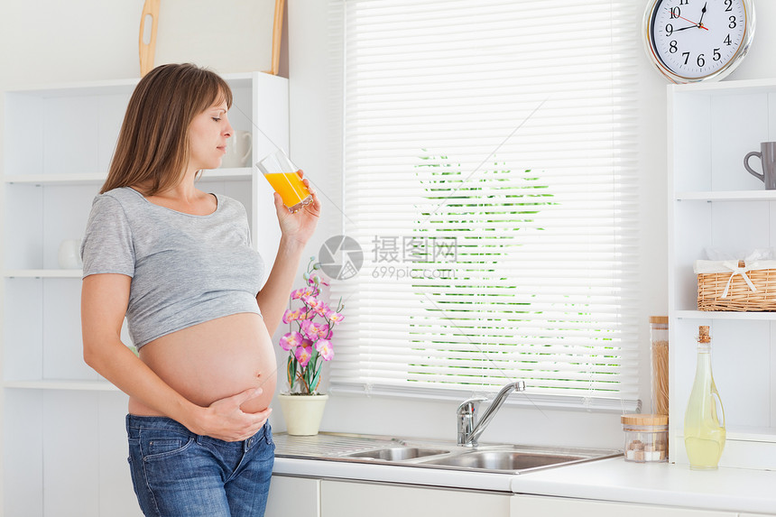 美丽的孕妇在喝杯橙汁时 会喝一杯橘子汁图片