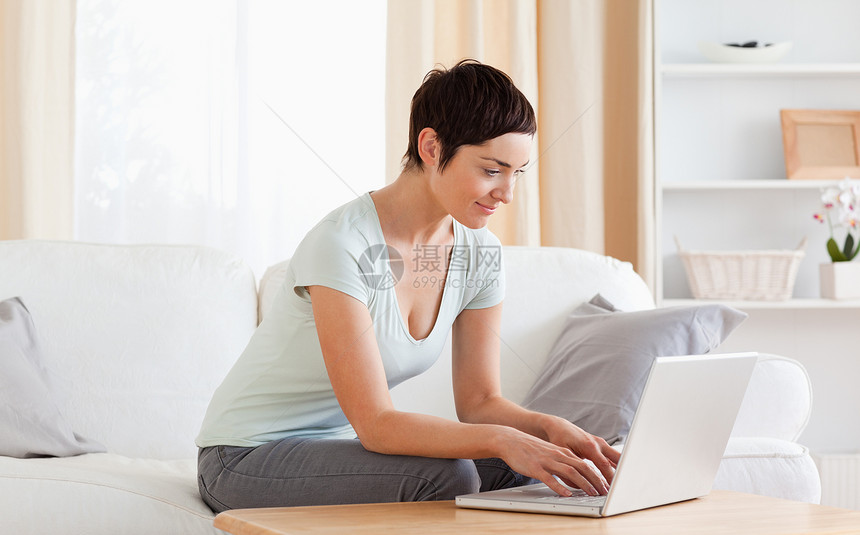 使用笔记本电脑工作的妇女享受房子喜悦快乐黑发互联网房间女士沙发微笑图片