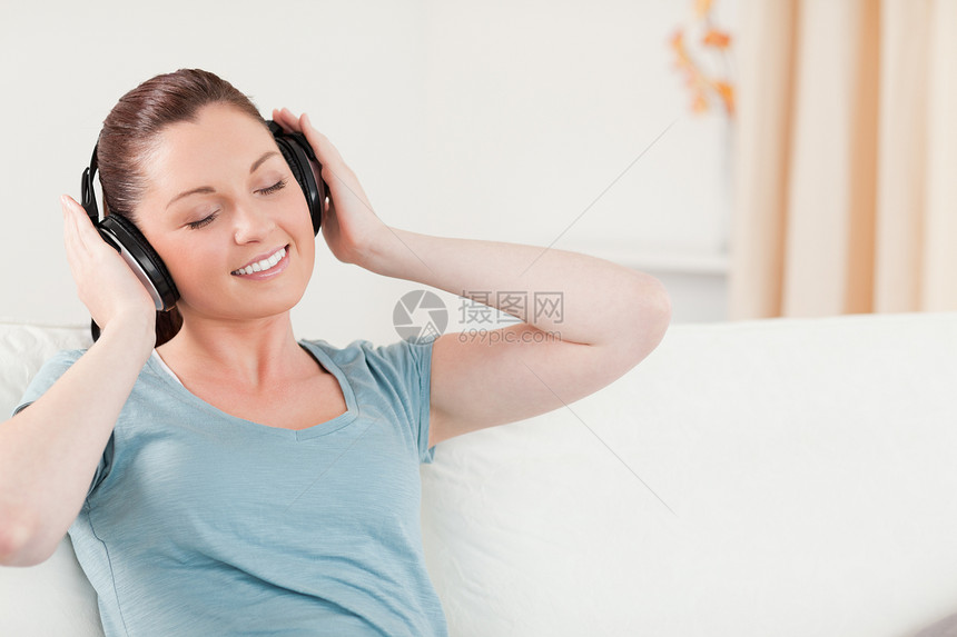 漂亮女人坐在沙发上 用耳机轻松放松图片