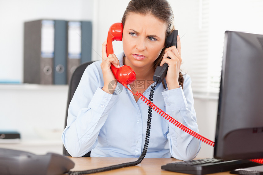 商业女商务人士用两台设备进行电话通话图片