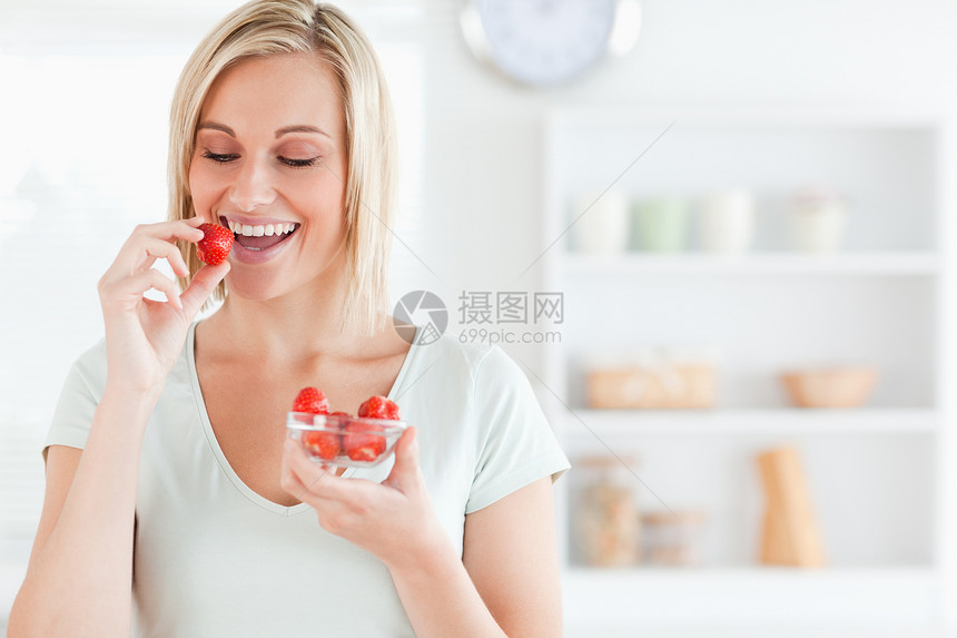 靠近一个享受的女人 吃草莓的近身图片