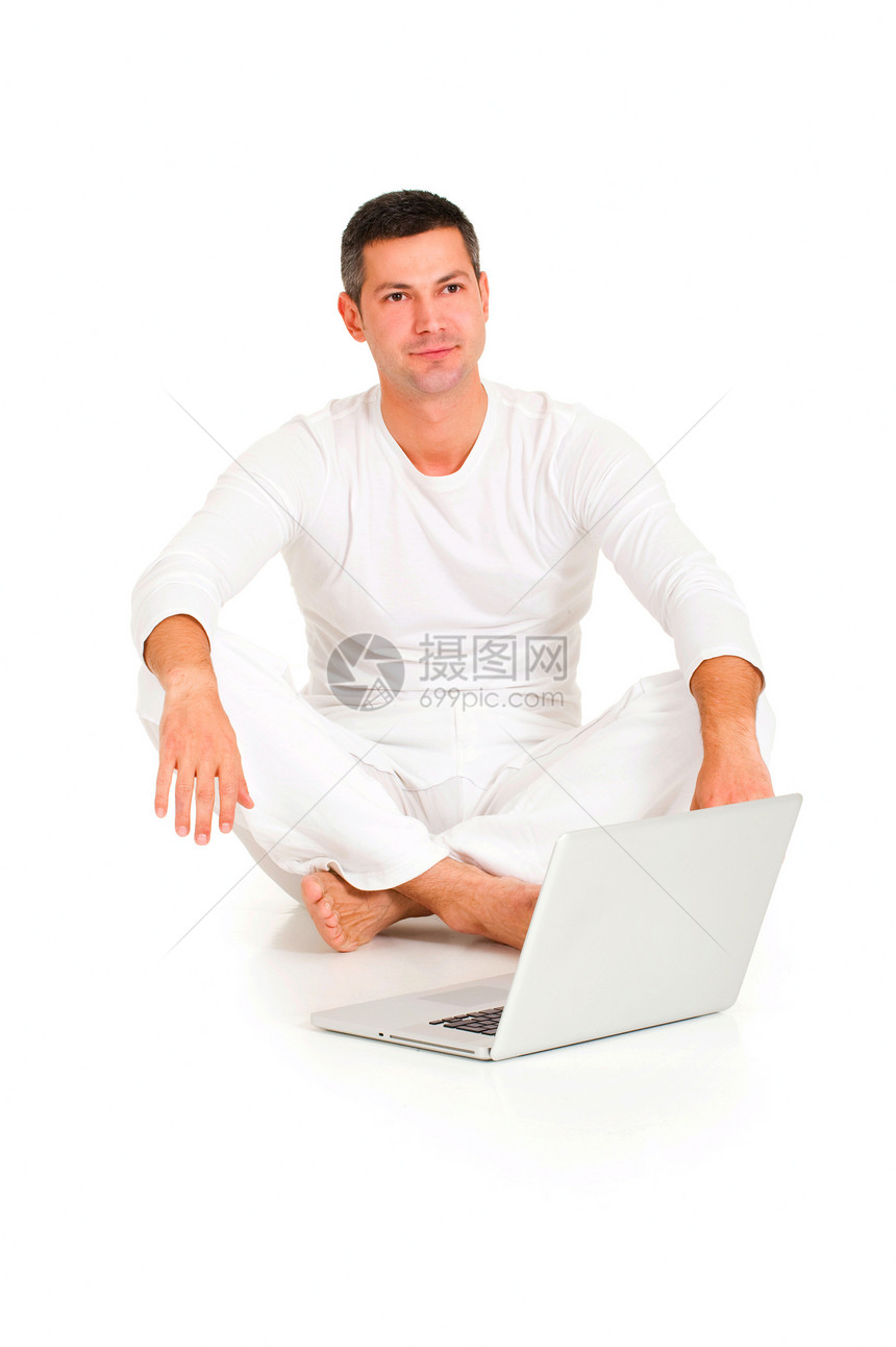 穿着白色衣服的男子用笔记本电脑坐在地板上图片