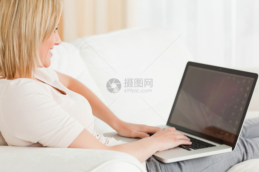 一个金发女人用笔记本贴近工人生活互联网电脑白色头发房间房子长椅女士图片