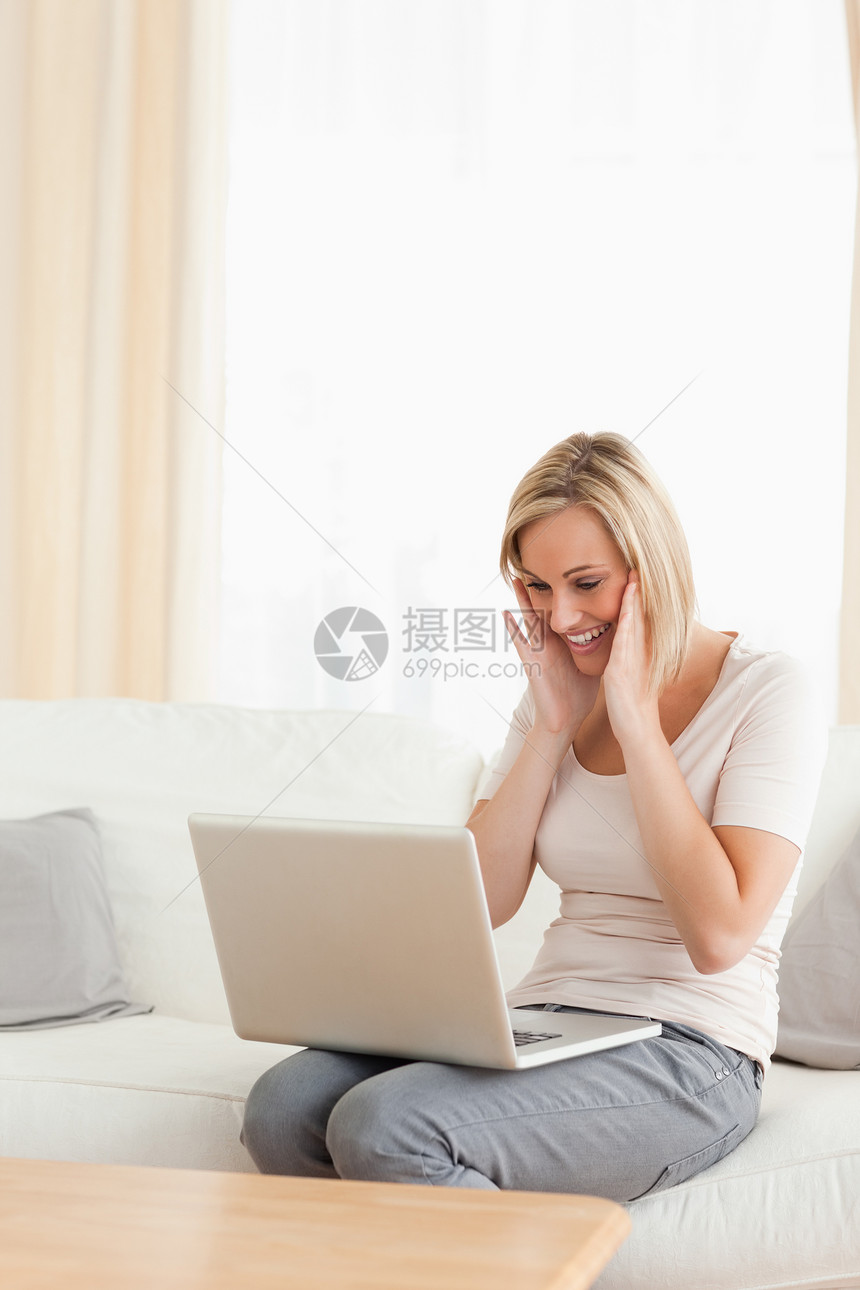 一个快乐的女人看着她的笔记本电脑的肖像图片