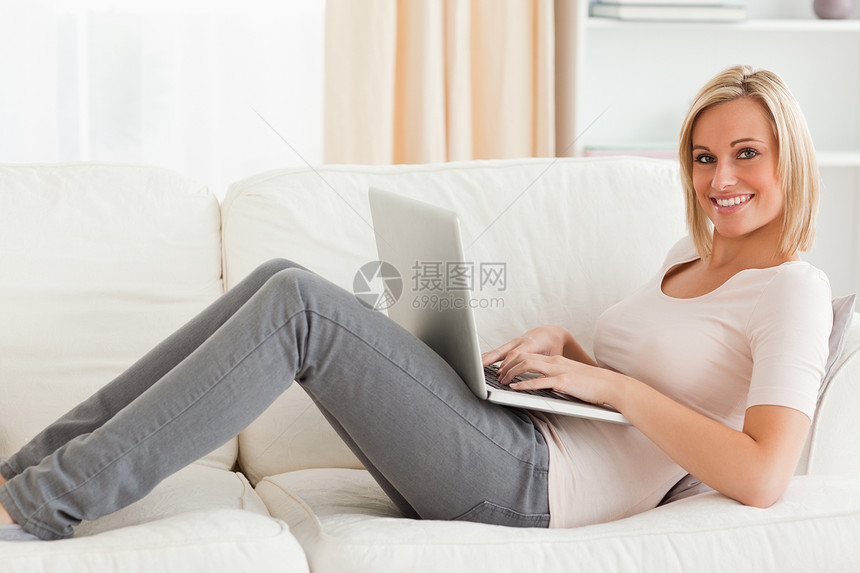 躺在沙发上时 带着笔记本电脑的笑女人图片