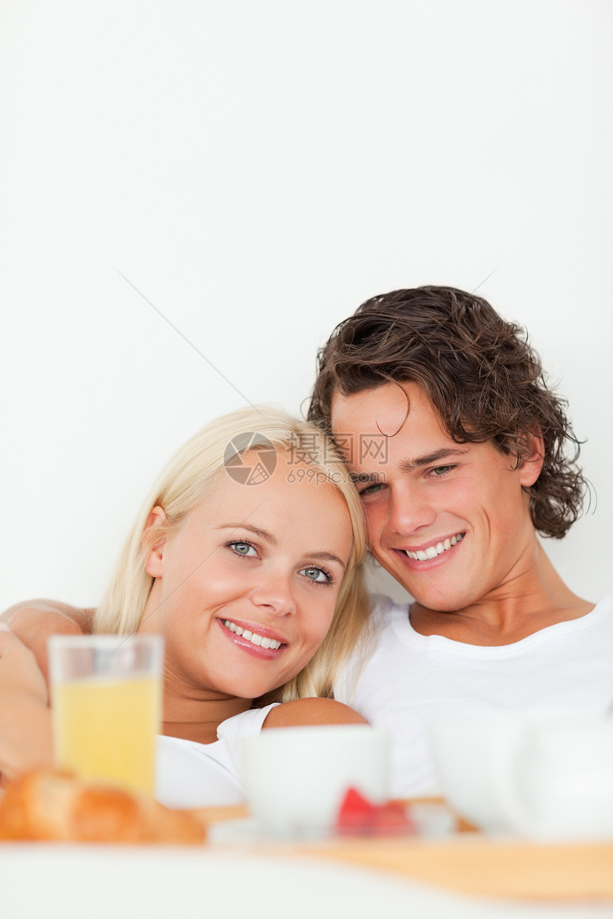 一对微笑的情侣吃早餐的肖像丈夫女性说谎休息室果汁金发杯子睡衣奢华酒店图片