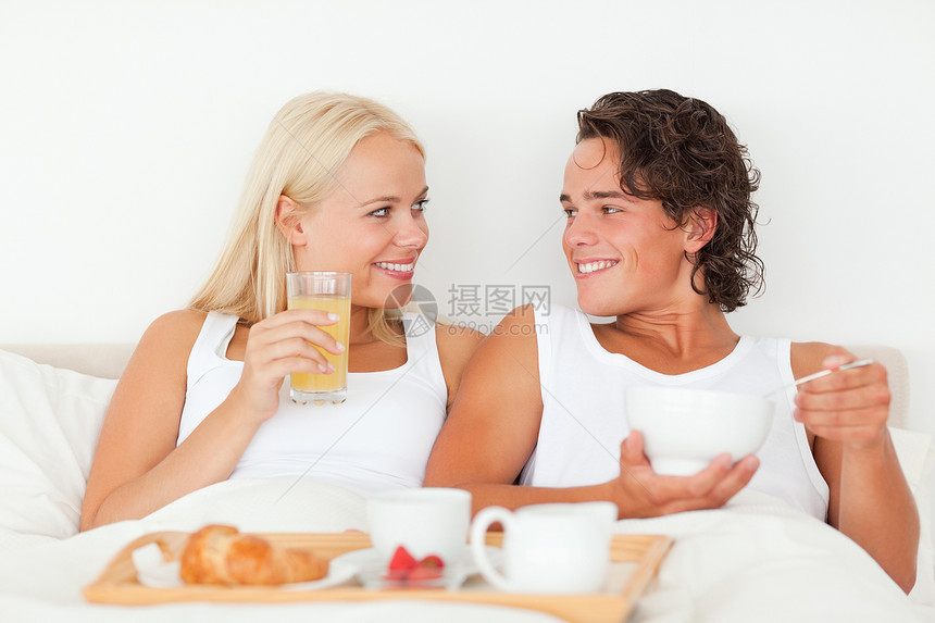 情侣在吃早餐时微笑丈夫枕头男人窗帘幸福卧室妻子奢华果汁乐趣图片