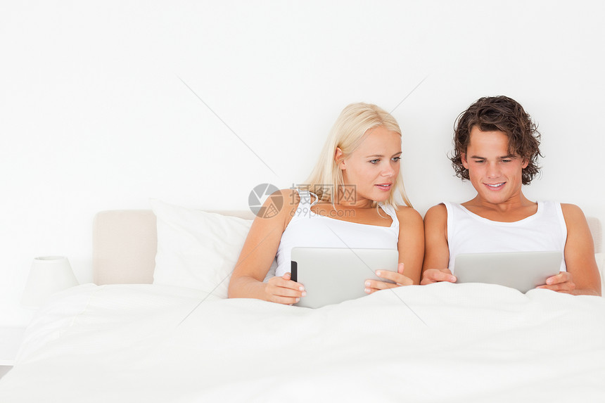 使用平板电脑的漂亮夫妇电子邮件阅读屏幕年轻人触摸屏房子微笑闲暇技术标签图片