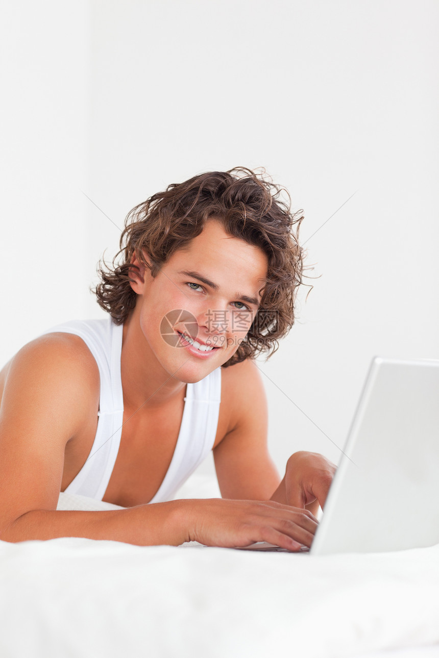 使用笔记本的人的肖像闲暇说谎年轻人电脑皮肤卧室娱乐技术互联网微笑图片
