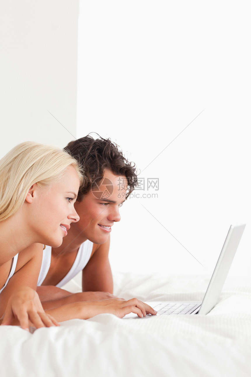 用笔记本画一对可爱夫妇的肖像年轻人互联网亲密感男人电脑笔记本快乐冲浪女性微笑图片