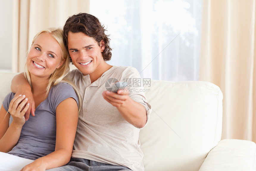 一对在看电视的夫妇控制电视闲暇频道交换沙发金发乐趣手表年轻人图片