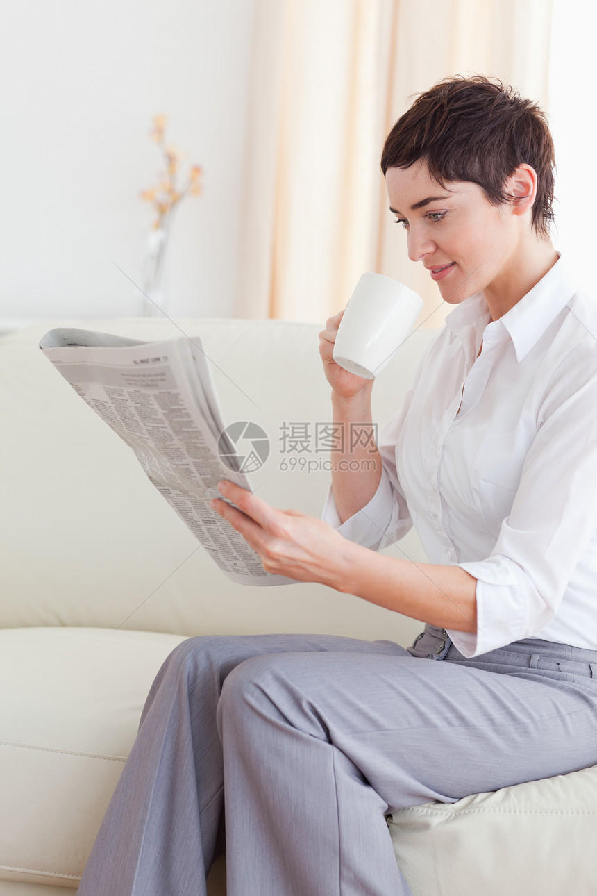 一名女性在看新闻时喝咖啡的肖像图片