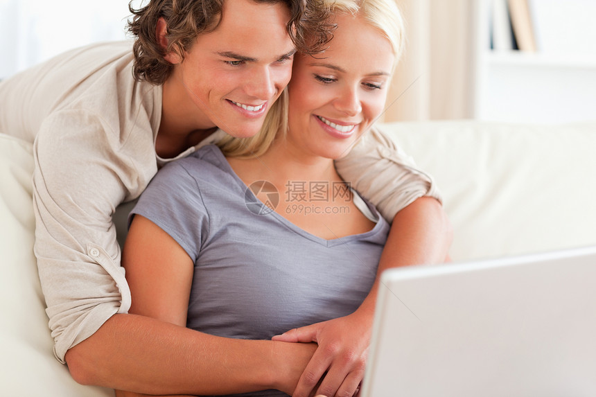 使用笔记本电脑的可爱年轻夫妇学习女性互联网工作成人房间乐趣沙发夫妻年轻人图片