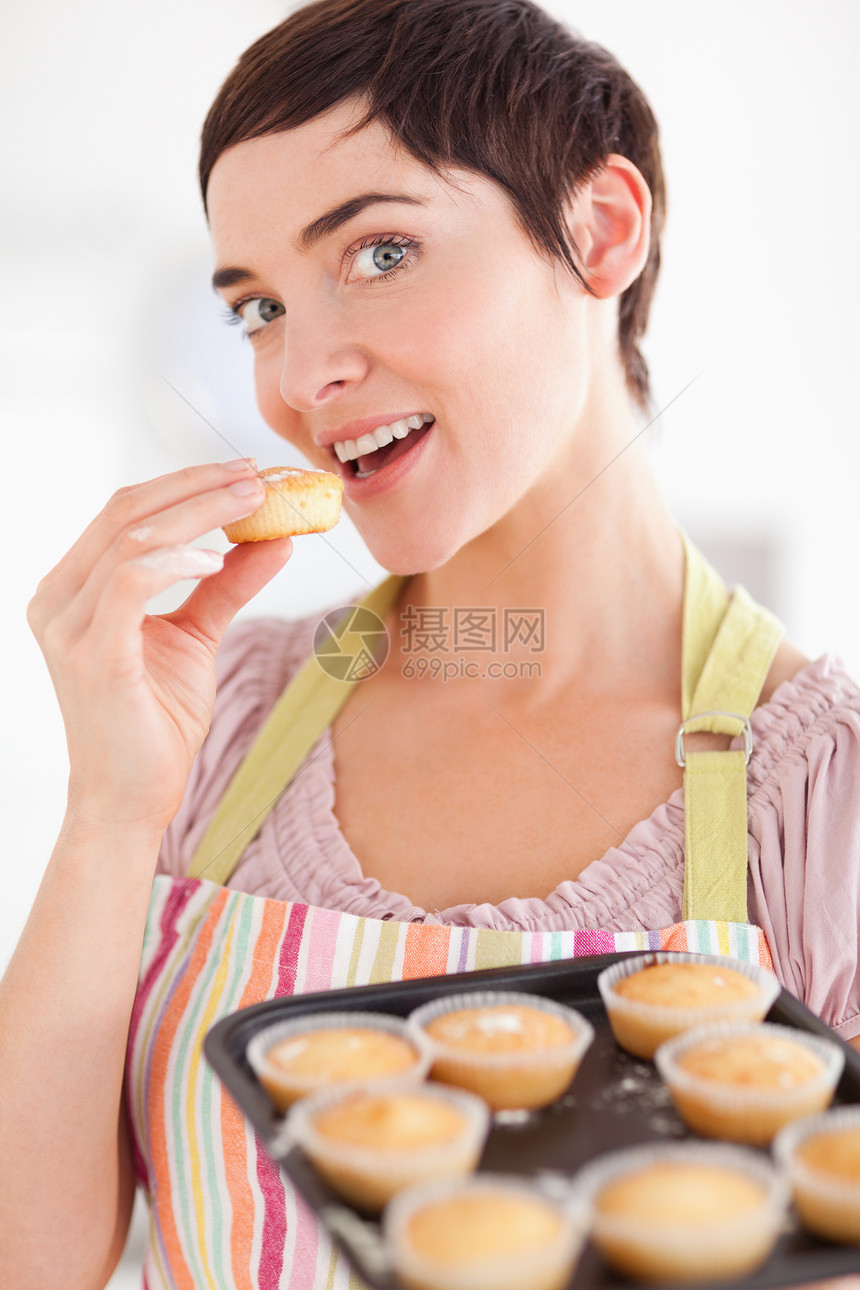 迷人的黑褐色女人在吃松饼时露出松饼图片