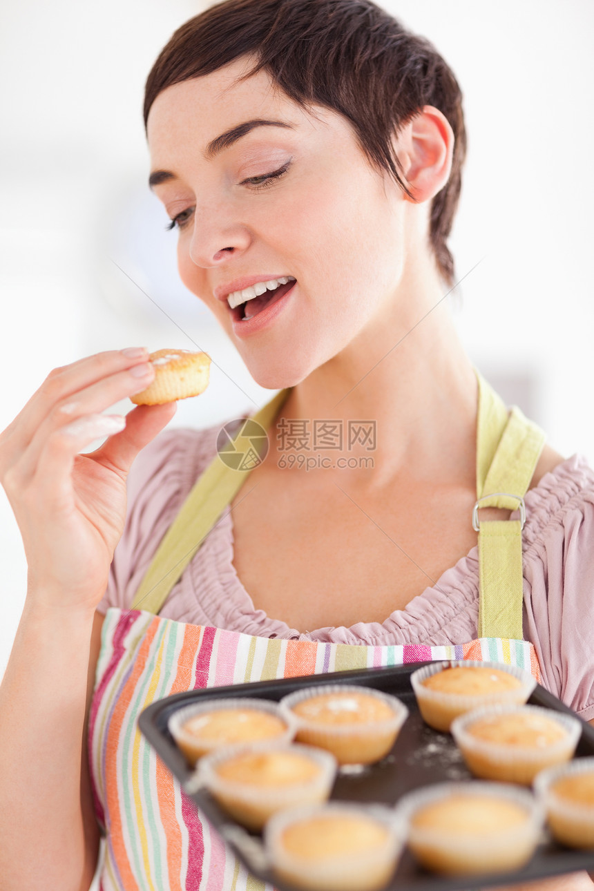 黑头发的笑脸女人在吃松饼时露出松饼图片